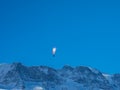 A paraglider in front of a snow covered mountain ridge in Switzerland