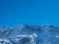 A paraglider in front of a snow covered mountain ridge in Switzerland