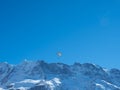 A paraglider in front of a snow covered mountain ridge in Switzerland