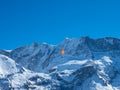 A paraglider in front of a snow covered mountain ridge in Switzerland