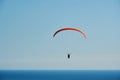 The paraglider hovers high in the sky above the blue sea Royalty Free Stock Photo