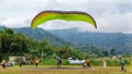 Paraglider pilot landing on green field in Batu City, East Java, Indonesia on July 8, 2023