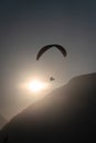 Paraglider over the silhouette of a wooded mountain ridge with the sun backlit Royalty Free Stock Photo