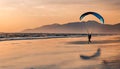 Paraglider pilot flies in the sky during sunset on beautiful beach. Paraplane silhouette. Adventure vacation and travel .