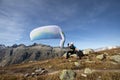 Paraglider pilot sits on a rock and balances his paraglider above his head near Lake Grimsel in the Swiss Alps