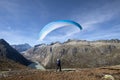 Paraglider pilot stands on a rock and balances his paraglider above his head near Lake Grimsel in the Swiss Alps
