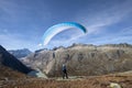 Paraglider pilot stands on a rock and balances his paraglider above his head near Lake Grimsel in the Alps