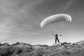 Paraglider pilot stands on a rock and balances his paraglider above his head near Lake Grimsel in the Swiss Alps