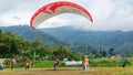 paraglider pilot with red and white parachute landing on field in Batu City, East Java, Indonesia on July 8, 2023