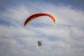 Paraglider on a red with yellow stripes paraglider flies in a blue sky with white clouds Royalty Free Stock Photo