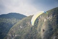 Paraglider with a wing gliding in the air in front of a mountain in bohinj, slovenia, in julian alps during a sunny afternoon. Royalty Free Stock Photo