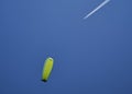 A paraglider with a yellow-green parashute and an airplane.