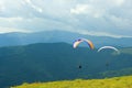 Paragliders flying low over top of Carpathian green mountains Royalty Free Stock Photo