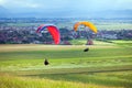 Paragliders flying over green fields