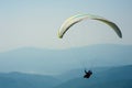 A paraglider flies over a mountain valley on a sunny summer day. Royalty Free Stock Photo