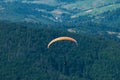 Paraglider flies over a mountain valley on a sunny summer day. Royalty Free Stock Photo