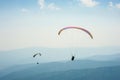 Two paragliders fly over a mountain valley on a sunny summer day. Royalty Free Stock Photo