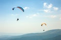 Two paragliders fly over a mountain valley on a sunny summer day. Royalty Free Stock Photo