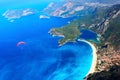 Paragliding flight over the blue lagoon of the Mediterranean Sea. Red dome of the parachute against the blue sea. Turkey. Oludeniz