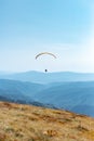 Paragliding in mountains. Freedom to fly in air over mountains with parachute. Paragliding behind blue sky Carpathian Royalty Free Stock Photo