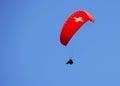 Paraglider with red wing shape on the blue sky in Interlaken, Switzerland.