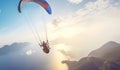 Paragliding in the sky. Paraglider tandem flying over the sea with blue water and mountains in bright sunny day. Extreme sport. Royalty Free Stock Photo