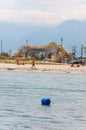 Pedestrian bridge above water canal, tourists resting on the Aegean sea beach, Mount Olympus on the background Royalty Free Stock Photo