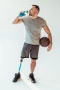 paralympic basketball player with basketball ball drinking water from sportive bottle