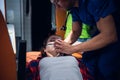 Paramedic presses an oxygen mask to a woman`s face, who is lying on a stretcher in an ambulance car