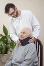 Paramedic puts an orthopedic collar on the neck of a very old woman.