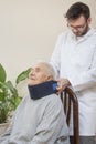 Paramedic puts an orthopedic collar on the neck of a very old woman.