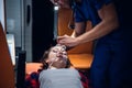 A paramedic puts on an oxygen mask on an injured woman lying on stretcher in the ambulance car