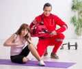 Paramedic in red visiting young woman in gym Royalty Free Stock Photo