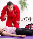 Paramedic in red visiting young woman in gym Royalty Free Stock Photo