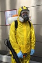 Paramedic wearing yellow protective costume and mask disinfecting coronavirus with the motorized backpack atomizer and sprayer