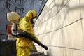 Paramedic wearing yellow protective costume and mask disinfecting coronavirus with the motorized backpack atomizer and sprayer