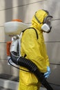 Paramedic wearing yellow protective costume and mask disinfecting coronavirus with the motorized backpack sprayer