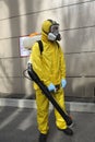 Paramedic wearing yellow protective costume and mask disinfecting coronavirus with the motorized backpack atomizer and sprayer