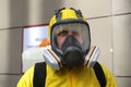 Paramedic wearing yellow protective costume and mask disinfecting coronavirus with the motorized backpack atomizer and sprayer