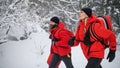 Paramedics from mountain rescue service running outdoors in winter in forest.