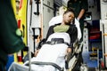 Paramedics moving a patient on a stretcher into an ambulance