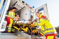 Paramedics putting injured man on stretcher in ambulance car