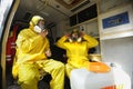 Paramedics sitting in the ambulance car putting yellow protective costumes and masks on preparing to disinfect coronavirus