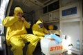 Paramedics sitting in the ambulance car putting yellow protective costumes and masks on preparing to disinfect coronavirus