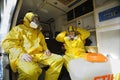 Paramedics sitting in the ambulance car putting yellow protective costumes and masks on preparing to disinfect coronavirus