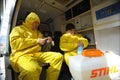 Paramedics sitting in the ambulance car putting yellow protective costumes and masks on preparing to disinfect coronavirus