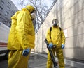 Paramedics wearing yellow protective costumes and masks disinfecting coronavirus with the motorized backpack atomizer and sprayer