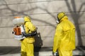 Paramedics wearing yellow protective costumes and masks disinfecting coronavirus with motorized backpack atomizer and sprayer