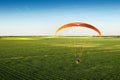 Paramotor flying a rapeseed field with blue sky