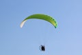 Paramotor pilot flying in a blue sky